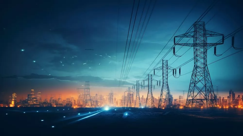 A high-voltage tower and power lines amidst the abstract blur of city lights at night